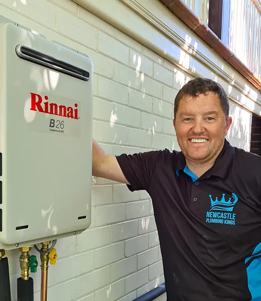 Plumber beside a newly installed continuous-flow gas hot water unit