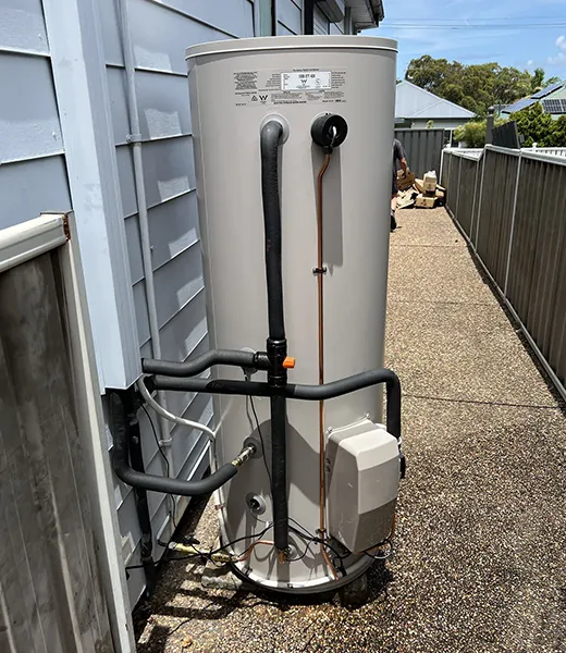 Storage hot water unit fitted against a house wall